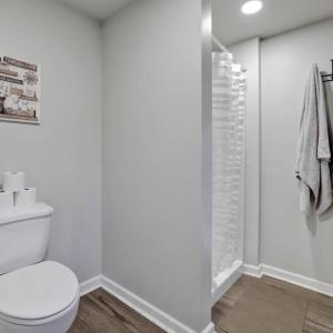 toilet and shower with towels hanging next to it