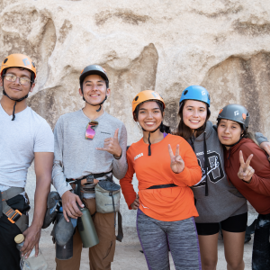 Young people in climbing gear standing and smiling together