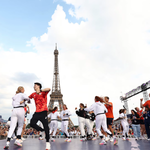 People on a stage dancing with the Eiffel Tower behind them
