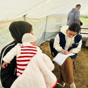 Woman holds baby while being assessed by an Action Against Hunger staff member. 