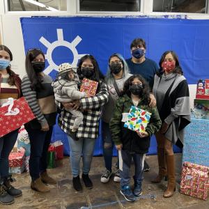 AEG employees surround a family at CARACEN in Los Angeles with presents for the holidays.