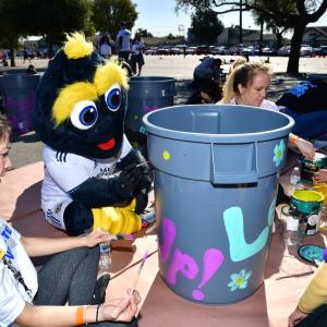 AEG volunteers join LA Galaxy's mascot Cozmo to paint trash cans.