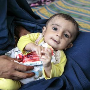 A young boy eats Plumpy'Nut, a peanut paste used to treat malnutrition, at one of Action Against Hunger's nutrition centers in Afghanistan's Helmand province. / Photo by Sandra Calligaro