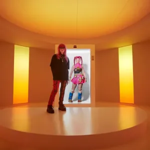 A person stood in front of a screen displaying an AI avatar 