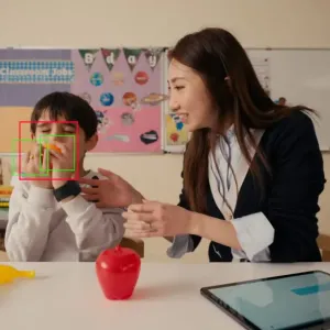 A child and a teacher sat at a desk in a classroom
