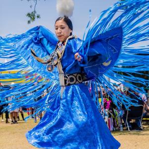 A person dancing in bright blue traditional dress.