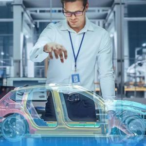 A person holding a hand over a holographic digital sketch of a car.