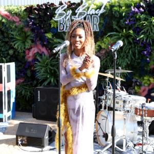 ByBlack Bazaar Co-host, Zerina Akers standing in front of a microphone.
