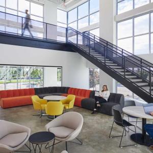 A lobby with people sat down on colourful seats and at a table