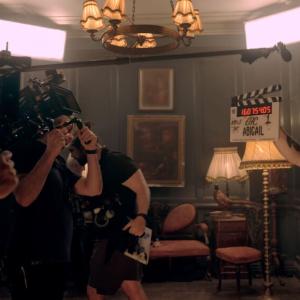 Camera crew on a film set, another with a clap-board "Abigail" on it.