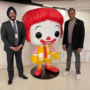 Abiman and Nick next to a large Ronald McDonald statue
