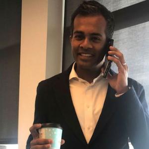 Abiman Rajadurai talking on a cell phone, smiling