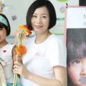 On the left, Wendy Wang, President of Mary Kay Asia Pacific region holding a young child whilst stood next to another person holding flowers