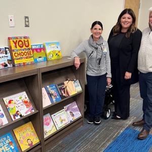 Sherry Iverson, director of patient and family support services at St. Luke's Children's Hospital; Jaime Gaudet; and Jason Gaudet visit the hospital’s Growing Minds Bookshelf.