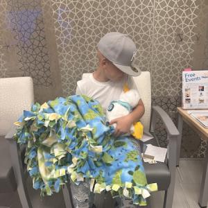 Young child holding an Aflac Duck and a blanket.