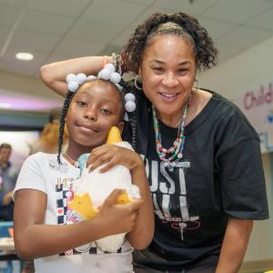 Aflac Coach Dawn Staley shown with a young female patient holding an Aflac My Special Duck.