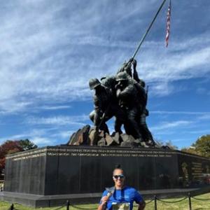Aflac team member Jeremy showing his medal in front of the Iwo Jima memorial.