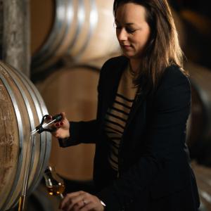 Agathe Boinot sampling liquid from a wooden barrel.