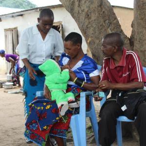 Agnes (In white), provides guidance to a breastfeeding mother in Mgandu.