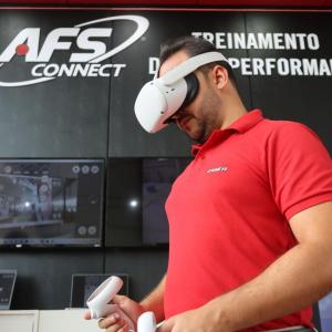 A person in VR headset, using controllers. "AFS connect" sign behind them.