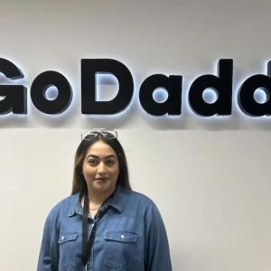 Aisha shown underneath a GoDaddy sign at work.
