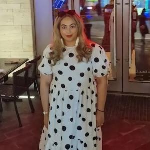 Aisha shown at a dinner in a white polka dot dress.