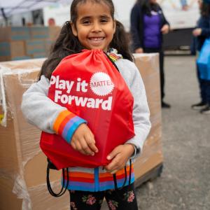Child holding a Mattel Play it Forward bag
