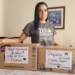 A person standing in a home, two boxes in front of them hand decorated with encouraging messages.