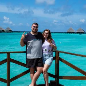 Alexander Ivanov and his wife in front of a beautiful blue ocean.