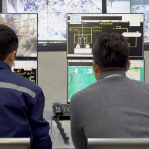 An Alibaba Cloud engineer works with an operator at a waste management plant.