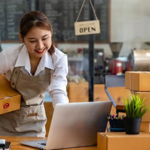 Female business owner packing boxes for shipping.