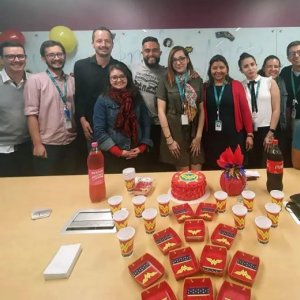 Angie and many coworkers stand behind a table with cake and party supplies