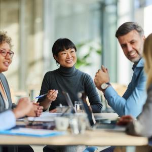 Team of five coworkers sitting around a table and smiling