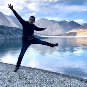 Arpan Gupta leaping in the air in front of a lake.
