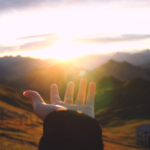 hand reaching out looking at sunrise
