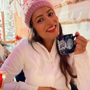 Ashwini seated and drinking a beverage. 