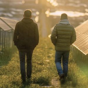 Two people walking through field with solar panels