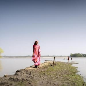 A woman walks along a flooded field. 