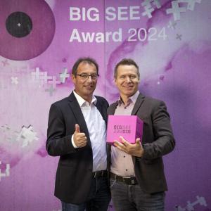 Two people stood together holding an award 