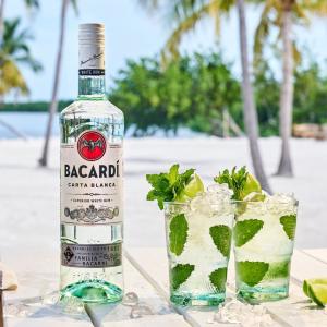 bottle of bacardi rum and cocktails with a beach in the background