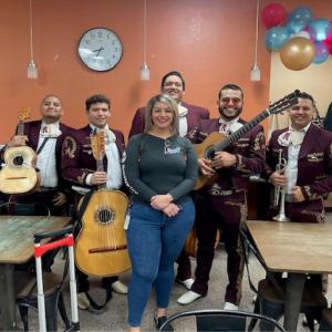 An employee standing with a mariachi band in a break room.