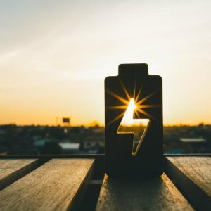 A cut out of a battery symbol on a table, showing the sunsetting in the gap