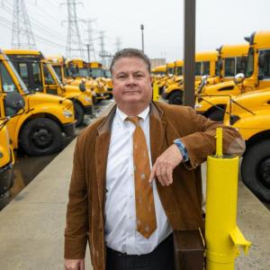 Man posing with school buses
