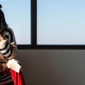 Benita Harrington sat on a bench in front of a window 