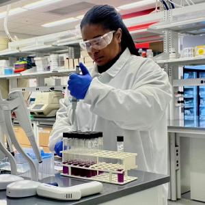 Scientist Bernice Karlton-Senaye, Ph.D. adds liquid to test tubes in a laboratory