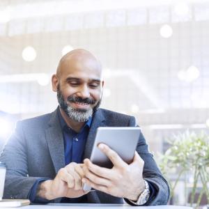 Man seated at a table with a tablet.