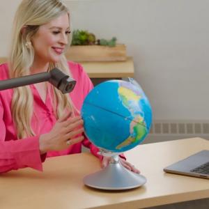 Woman sitting in front of computer with globe next to her on the desk