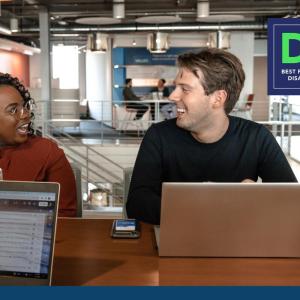 Two people using laptops and talking