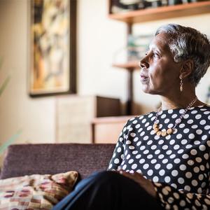 Person sitting on a couch in a living room setting looks towards a window