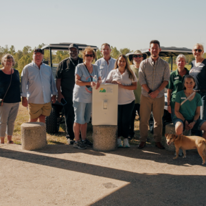 Group of people and a dog stand around in sunny area with oversized prop light switch.